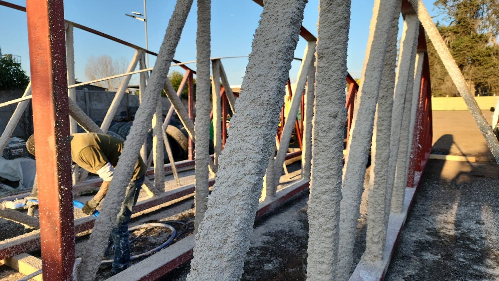 Operario aplicando mortero ignífugo en estructura metálica industrial